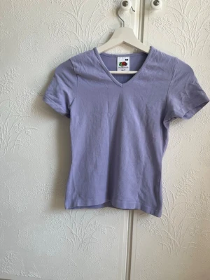 Ljuslila v-ringad t-shirt Fruit of the Loom - Säljer en ljuslila v-ringad t-shirt från Fruit of the Loom i modellen Lady-Fit. T-shirten har korta ärmar och är gjord i mjuk bomull, perfekt för en avslappnad och stilren look.