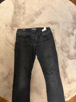 Svarta Ltb jeans med slitningar - Säljer ett par svarta jeans med raka ben och diskreta slitningar. Jeansen har fem fickor och klassisk passform. Materialet är denim med en något tvättad look. Perfekta för en avslappnad stil .Använt cirka 3 gången, sen har den bara legat hemma. Det är ett par Ltb jeans och jeansformen heter Valery.Storleken är w26 L32