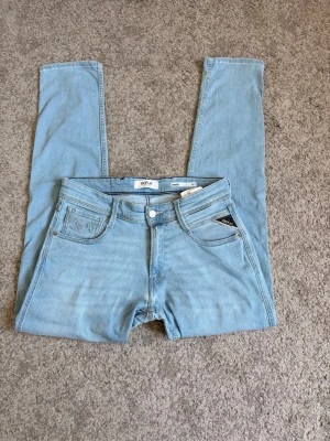 Ljusblå jeans från Replay - Säljer ett par ljusblå jeans från Replay med klassisk femficksmodell och raka ben. Jeansen har en snygg patch bak i midjan och detaljerade sömmar på bakfickorna. Perfekta till en avslappnad stil och passar till det mesta.