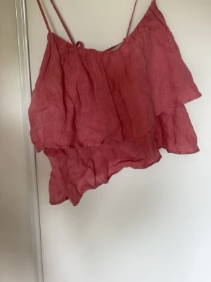 Rosa linnetopp med volanger från Zara - Supersöt rosa linnetopp från Zara med tunna axelband och dubbla volanger. Toppen är gjord i linne och är luftig. Säljer pågrund av att den är för liten, enbart använd några gånger!