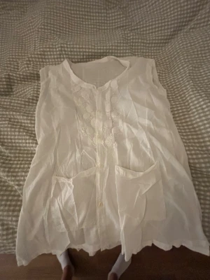 Vit blus - Jättesöt vit blus med blom detaljer och små fickor på framsidan. 