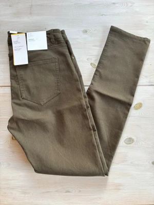 Khakigröna skinny jeans från H&M - Säljer ett par khakigröna skinny jeans från H&M med superstretch för extra bekväm passform. Jeansen har hög elasticitet och håller formen länge. Klassisk femficksmodell och smal siluett som passar till många olika stilar. Helt nya!