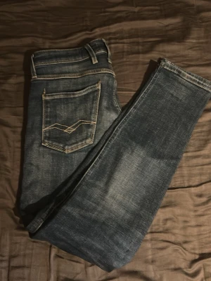 Replays slim fit blå - Snygga blå slim fit jeans med ljusa slitningar och kontrastsömmar. Klassisk femficksmodell med cool detaljsöm på bakfickan. Perfekta till en avslappnad streetstyle-look. Tillverkade i stretchigt denim för skön passform. Strl w29 L30