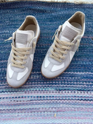 Vita Maison Margiela gats - Helt nya vita Maison margiela gats i storlek 43, köpta från nk, kvitto tillkommer samt dustbagsen,  boxen medföljer tyvärr inte, innersulan är 27,3cm, hojta till vid funderingar!