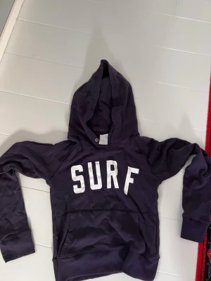 Mörkblå hoodie från Kapital SURF - Im selling Kapital K, Iconic ”surf” hoodie. Pre owned, good quality. Doesn’t fit me. The sleeves are longer than in normal hoodies and it is a little bit cropped or tight on the stomach! 