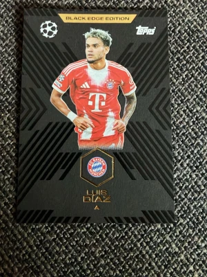 Topps Black Edge Edition samlarkort - Unikt samlarkort från Topps Black Edge Edition med fotbollsspelaren Luis Diaz i Bayern Münchens röda matchtröja. Kortet har svart bakgrund med guldtext och klubbens logga. Perfekt för samlare av fotbollskort.