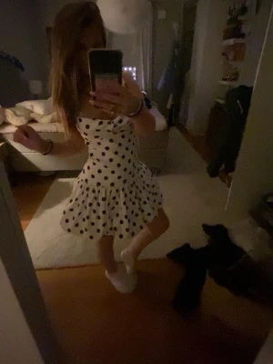 Vit zara klänning med svarta prickar - Supersöt vit klänning med svarta prickar och volang nedtill. Klänningen är kort samt en figurnära passform upptill. Perfekt för sommarens alla tillfällen