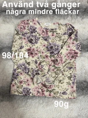 Blommig långärmad topp i pastell - Söt topp med blommigt mönster i lila, rosa och grönt på ljus botten. Långärmad modell med resår vid ärmslut och rund halsringning. Perfekt för dig som gillar romantisk och feminin stil.🌸 Sparsamt använd. Några mindre fläckar. 98/104 