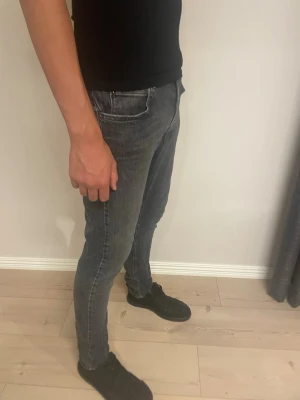 Svart gråa slim fit jeans herr från replay  - Snygga grå slim fit jeans med klassisk femficksdesign och normal midja. Jeansen har en tvättad look och smal passform som sitter tajt längs benen. Perfekta för dig som gillar en modern och stilren stil.