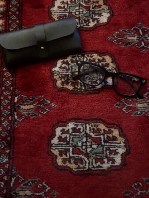 Svarta solglasögon med silverdetalj - Säljer ett par svarta solglasögon med rektangulär form och snygg silverdetalj vid gångjärnen. Glasögonen har en klassisk look och kommer med ett svart fodral. Perfekta för dig som vill ha en stilren accessoar.