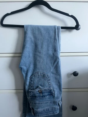 True Religion Jeans - Midwaist jeans från True Religion i modell Becca, jeansen är ej uppsydda och kommer i orginallängd. Jeansen har en defekt då ena knappen till bakfickan lossnat och sedan limmats på igen vilket syns på sista bilden. ❣️