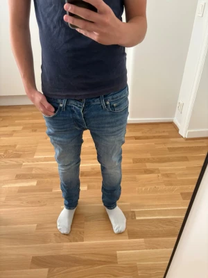 Jack & Jones jeans  - Säljer ett par blå slim fit jeans med klassisk femficksdesign och normalhög midja. Jeansen har en snygg tvätt med lätt slitningar och smal passform hela vägen ner. Perfekta till vardagslooken och passar till det mesta.