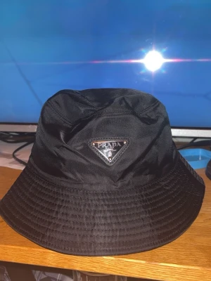 Svart bucket hat från Prada - Säljer en svart Prada hat för skönt pris, priset kan diskuteras sänkas vid en snabb affär