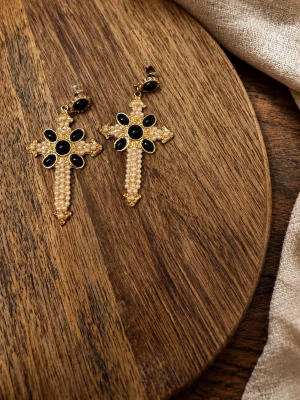 Korsörhängen med pärlor och svarta stenar - Säljer ett par statement örhängen i form av kors, dekorerade med små vita pärlor och svarta ovala stenar. Örhängena har guldfärgade detaljer och en lyxig vintagekänsla. Perfekta för dig som vill sticka ut med accessoarer som syns.