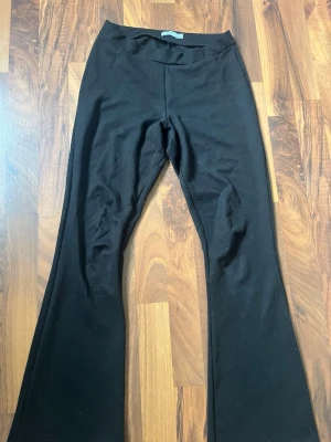 Svarta bootcut leggings - Säljer ett par svarta leggings med bootcut-modell och hög midja. De är stretchiga och sitter tajt över låren men har utsvängda ben. Perfekta till sneakers eller boots och superbekväma för en avslappnad stil.