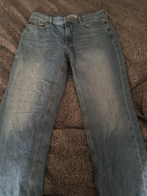 Blå raka jeans från ONLY - Snygga blå jeans från ONLY med rak passform och klassisk femficksdesign. Jeansen har en ljus tvätt med diskreta slitningar framtill och normal midja. Perfekta för en avslappnad och trendig look.