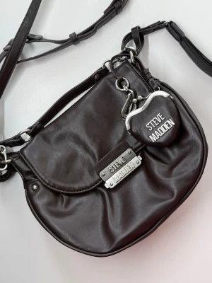 Mörkbrun axelremsväska Steve Madden - Mörkbrun axelremsväska från Steve Madden 