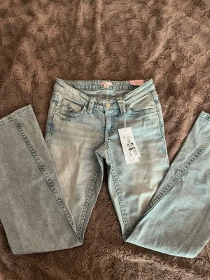 Ljusblå utsvängda lågmidjade jeans - Snygga ljusblå jeans som är utsvängda och lågmidjade. Baksidan har detaljer på fickorna och knappar. Helt oanvända endast testade 