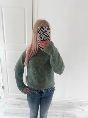 Kashmir tröja - Enkel och stilren stickad tröja i en dämpad grön färg. Tröjan har rund halsringning, långa ärmar och en rak passform. Perfekt att matcha med jeans för en avslappnad look.