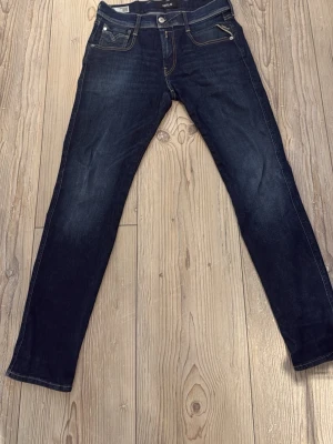 Replay Anbass - Snygga mörkblå slim fit jeans med klassiska fem fickor och kontrastsömmar. Jeansen har dragkedja och knapp framtill samt coola detaljer på bakfickorna. Perfekta för en trendig stil. Kom gärna med frågor och bud!!