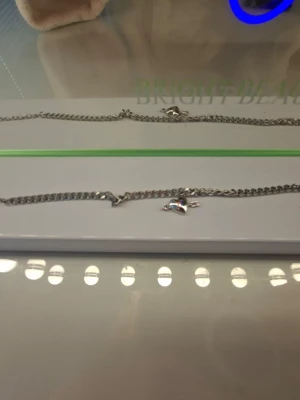 Silverfärgat halsband med hjärthänge - Stilrent halsband i silverfärgad metall med en klassisk kedja och ett hjärthänge med pil genom. Perfekt accessoar för dig som gillar romantiska och edgy detaljer. Halsbandet har ett smidigt karbinlås och passar till många olika looks.