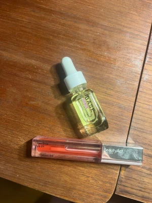 BeautyAct Dew Drop Lip Oil - Säljer en Dew Drop Lip Oil från BeautyAct med hyaluronsyra. Läppoljan kommer i en genomskinlig rosa tub med svart lock och applikator. Ger glans och återfuktar läpparna med en lätt oljig känsla och nagel olja .