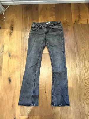 Grå bootcut jeans med slitningar - Säljer ett par grå bootcut jeans med lätt slitna detaljer och klassisk femficksmodell. Jeansen har utsvängda ben och kontrastsömmar. Passar perfekt till en avslappnad och trendig stil.