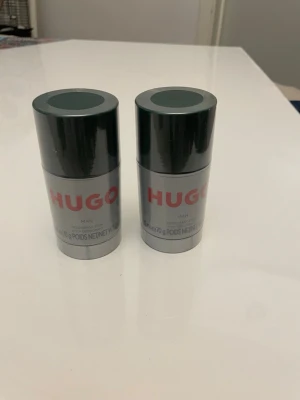 HUGO MAN deostick 2-pack, NYA - Två stycken HUGO MAN deostick i stilren grå och mörkgrön design. Båda är inplastade/oöppnade. Perfekt för dig som vill ha en fräsch och maskulin doft i vardagen. Praktisk och smidig att ta med i väskan. Varje stick innehåller 70g.