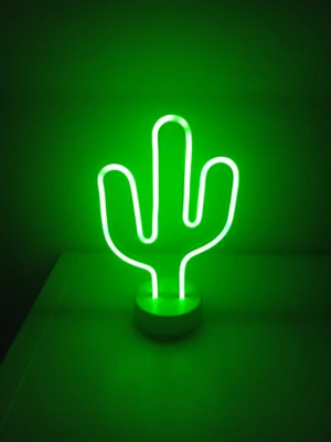 Grön kaktusformad neonlampa - Cool neonlampa i form av en kaktus som lyser starkt grönt. Lampan står på en rund vit fot och är tillverkad av plast och LED-rör. Perfekt som dekoration i sovrummet eller på skrivbordet för en trendig vibe.        Batterier ingår!