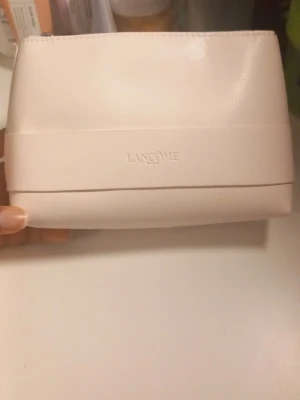 Lancôme necessär med tillagd hudvård - Säljer en stilren, ljusbeige necessär från Lancôme i slätt material med tillagd hudvård. Perfekt för dig som gillar exklusiv hudvård och snygga accessoarer till sminkbordet.