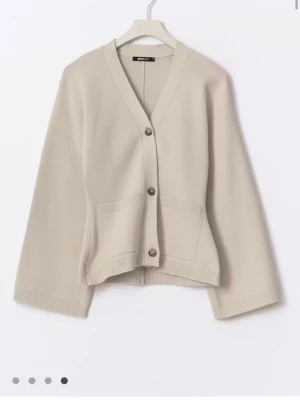Beige kofta med fickor och knappar - Stilren beige kofta med v-ringning och tre knappar framtill. Koftan har två praktiska fickor och breda ärmar för en avslappnad look. Tillverkad i mjukt stickat material som känns skönt mot huden. Perfekt att slänga över en t-shirt eller topp.