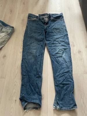Blå relaxed fit jeans från H&M - Säljer ett par blå jeans från H&M i relaxed fit-modell. Klassisk femficksdesign med raka ben och normal midja. Jeansen är tillverkade i denim och har kontrastsömmar. Perfekta för en avslappnad och trendig stil.