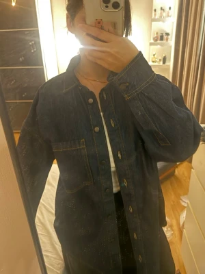Mörkblå oversized jeansjacka  - Säljer en mörkblå oversized jeansjacka med klassisk krage och tryckknappar framtill. Jackan har kontrastsömmar, en bröstficka och raka ärmar. Perfekt för en avslappnad och trendig look. 