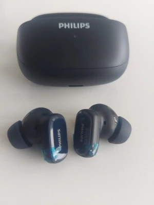 Philips trådlösa in-ear hörlurar - Snygga mörkblå trådlösa in-ear hörlurar från Philips med matchande laddningsetui. Hörlurarna har en modern, kompakt design och mjuka silikontoppar för bekväm passform. Perfekta för musik, poddar och samtal på språng.