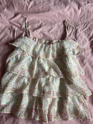 Volang topp  - Somrig volang topp med blommor på som även funkar att ha på sig året runt. (Använd 3x) originalpris (400kr) går att justera banden. Är i storlek m med passar även för folk med xs och s. 