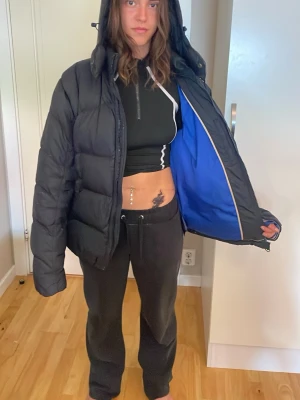 Svart Tommy hilfiger pufferjacka med blått foder - Pris diskuteras vid snabb affär. Säljer en svart pufferjacka från Tommy Hilfiger med blått innerfoder och huva. Jackan har dragkedja framtill, vadderad design och en liten logga på ärmen. Perfekt för kalla vinterdagar, luftig och riktigt skön att bära