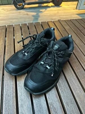 Svarta sneakers från Everest - Snygga svarta sneakers från Everest med robust sula och detaljer i både textil och syntet. Skorna har svarta snören med vita inslag och en sportig, modern look som passar till det mesta. Perfekta för dig som gillar en clean och stilren stil.