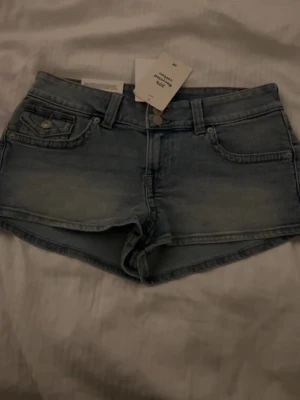Lågmidjade ljusblå jeansshorts - Snygga blåa shorts som inte kommer till användning. Prislappen är kvar aldrig använt. strl 38