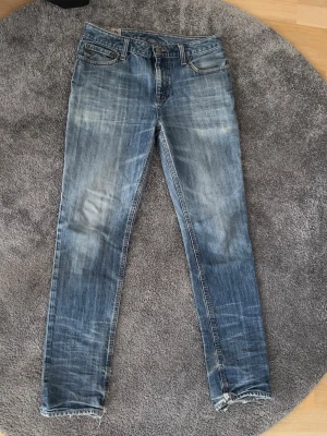Blå slitna slim / raka jeans Polo Ralph Lauren - Säljer ett par blå slim / raka jeans med slitningar och tvättade detaljer från Polo Ralph Lauren. Jeansen har klassisk femficksmodell och dragkedja. Perfekta för en avslappnad och trendig look. Märkt med skinny, men sitter mer som slim eller rak beroende på kroppsstorlek. Slitna vid byxbenens ände, se bild 5 och 6. Storlek 18 / ca 170.