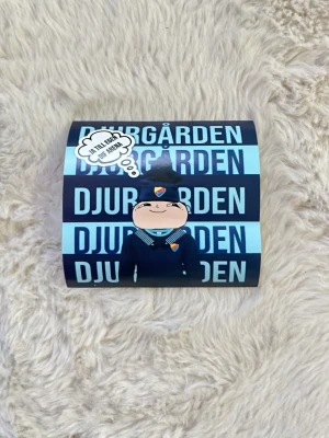 10st Djurgården klistermärke  - Klistermärke med Djurgården-tema i blått och svart. Motiv av en tecknad figur i supporterkläder och texten 'Tänk legendar, inte medgång'. Perfekt för att pimpa dator, mobil eller anteckningsbok.