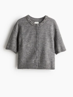 Grå croppad topp med pärlor - Snygg grå croppad topp med korta ärmar och pärldetaljer vid halsringningen. Toppen har en mjuk och stretchig känsla och stängs med knappar framtill. Perfekt för dig som vill ha en trendig och bekväm look.