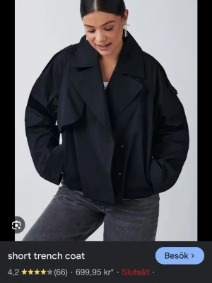 Svart trenchcoat gina - Svart oversized jacka med klassisk krage och knappar framtill. Jackan har en loose passform och är långärmad, perfekt för en avslappnad och trendig look. Passar bra till lager-på-lager och streetwear.