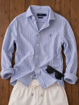 Blårandig skjorta från Polo Ralph Lauren - Säljer en klassisk blårandig skjorta från Polo Ralph Lauren med vit botten och blå vertikala ränder. Skjortan har lång ärm, knappar framtill och den ikoniska broderade loggan på bröstet. Perfekt till jeans eller shorts för en clean look.