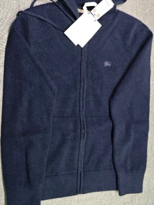  Burberry zip tröja - Jag säljer helt ny sällsynt mörkblå burbery tröja med dragkedja framtill och huva. Pris kan diskuteras vid snabb affär. Tröjan är Tillverkad i mjukt material och har en burberry logga broderad på bröstet.  Perfekt för dig som gillar en enkel och stilren look. Passar till det mesta och är superbekväm. 