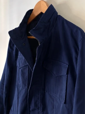 Field jacket - Snygg mörkblå field jacket från navigare. Helt ny! Aldrig använd. Skriv vid funderingar! Nypriset ligger på ca 3000Kr.