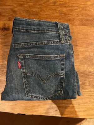 Blå raka jeans från Levi's - Klassiska blå jeans från Levi's med rak passform . Jeansen har den ikoniska röda Levi's-lappen på bakfickan och är tillverkade i slitstark denim. Perfekta för en avslappnad och tidlös stil.  