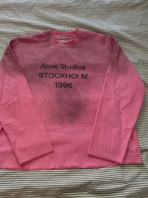 Rosa long sleeve Acne Studios - Säljer en rosa långärmad topp från Acne Studios med tryck Acne Studios STOCKHOLM 1996 på bröstet. Aldrig använt. Jag själv har croppat den men mått ser du på sista bilden.☺️