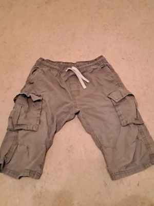Beiga cargoshorts från KappAhl - Jag säljer ett par shorts i mycket bra skick. De är väl omhändertagna och ser nästan nya ut. Perfekt för dig som vill ha ett par bekväma och snygga shorts till ett bra pris.  Priset är 35 kr, vilket jag tycker är ett riktigt bra pris med tanke på skicket. Jag är öppen för snabba affärer!  Tveka inte att höra av dig om du är intresserad eller har några frågor. Först till kvarn gäller!