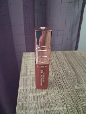 L'Oréal Hyaluron Lip Tint 640 Tea Time - Helt ny och oanvänd. Säljes pga fel färgval. ✨ Ger: Lätt tint + glans som torkar till mjuk matt finish Återfuktning med hyaluronsyra Viktlös färg som sitter länge Naturlig nude‑ton enligt beskrivning, Tea Time. Dubbelverkande formula – färg + serumkänsla 12 timmar viktlös färg enligt konsumenttest 60–80% omedelbar återfuktning beroende på källa Plumpande effekt (lätt utfyllande känsla) Mjuk applikator för enkel applicering