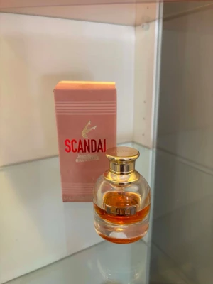 Scandal parfym med guldlock - Scandal parfym från Jean Paul Gaultier med rund glasflaska och elegant guldigt lock. Doften kommer i en rosa kartong med röd text och har en lyxig känsla. 